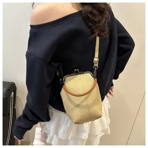 Detail einer beigen Canvas-Tasche mit Metallverschluss, braunem Griff und Schultergurt