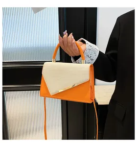Détail du sac en cuir orange et tissu beige avec garnitures métalliques dorées