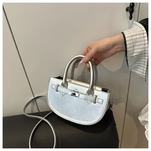 Dettaglio di una borsa a mano semicircolare argento con texture metallica e fibbia