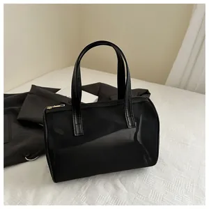 Detail view of a black mesh tote bag with smooth metal zipper and vegan leather handle