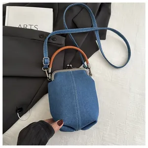 Detail der blauen Denim-Minihandtasche mit weißen Nähten und rundem braunem Ledergriff