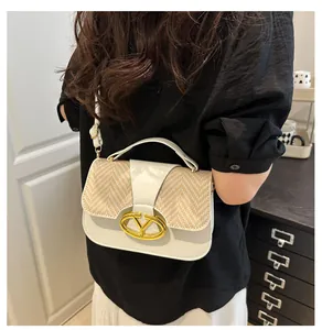 Detail of white leather and straw patchwork handbag with gold V-shape buckle