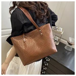 Close-up of brown woven texture tote bag with slim shoulder straps and silver rivets