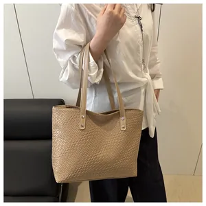Close-up of beige woven texture tote bag featuring silver rivets and durable double handles