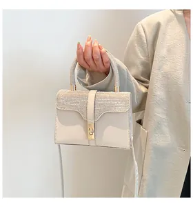 Detail einer beige Handtasche mit glitzernder Klappe und goldenem Drehverschluss