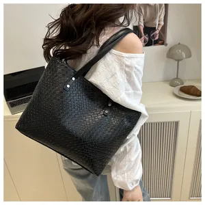 Detail view of woven texture and reinforced handles on a black oversized tote bag