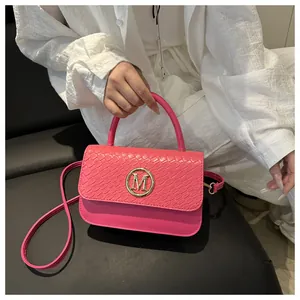 Détail du sac rose vif avec logo M doré et texture motif serpent sur le rabat