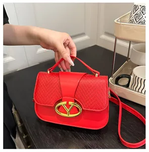 Close-up of red leather handbag featuring woven texture and golden V-shaped metal buckle