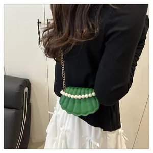 Detail of green shell-shaped crossbody bag with elegant pearl trim and gold chain