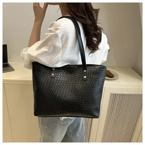Fashionable black woven leather tote bag shown on a model in a minimalist lifestyle setting