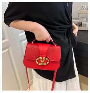 Detail showing the red woven leather texture and gold V-shaped metal buckle on the handbag