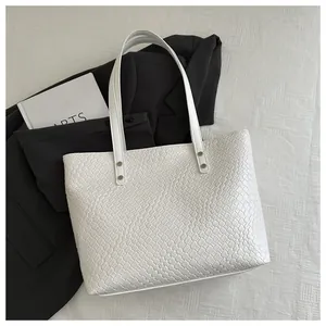 Detail of white woven texture tote bag with silver metal rivets and long shoulder strap