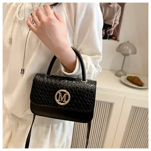 Vue détaillée du sac à main noir tressé avec logo M doré sur fond intérieur crème