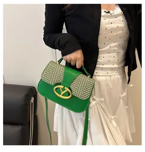 Detailed shot of green leather handbag featuring black and white woven pattern and gold clasp