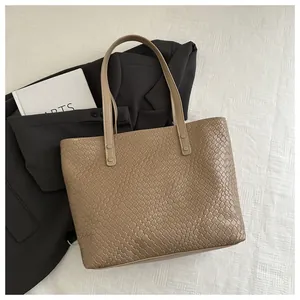 Detail of khaki woven leather tote bag with silver rivets and long shoulder straps