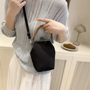Minimalistische schwarze Segeltuchtasche mit braunem Griff und Schultergurt im Trend