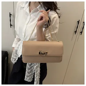 Detail view of beige crossbody bag with gold chain strap and elegant metallic buckle