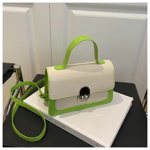 Detail of crossbody bag with beige canvas and neon green leather featuring silver buckle