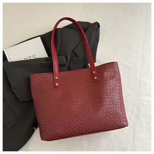 Detail shot of dark red woven tote bag featuring fine texture and silver rivet hardware