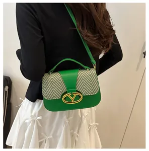 Detailed view of green leather shoulder bag with houndstooth weave and golden V-shaped lock