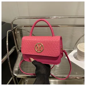 Détail de texture tressée et logo doré M sur sac à main en cuir rose fuchsia