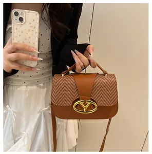 Detail of tan patchwork handbag with woven texture flap and golden V-shaped logo