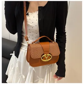 Detail shot of the gold metal buckle and woven texture on a brown crossbody bag