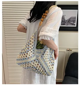 Detail of blue and beige crochet bag with wood bead strap and floral knit pattern