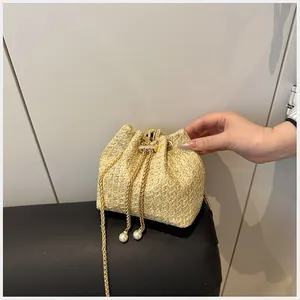 Détail du sac seau en paille avec texture tissée fine et élégant cordon perlé