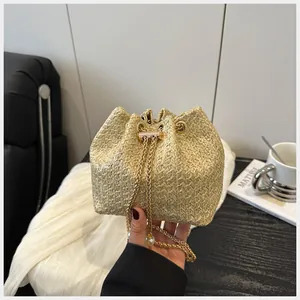 Détail du sac seau en paille avec cordon chaîne dorée et élégant pendentif en perle