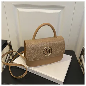 Détail d'un sac bandoulière kaki avec texture crocodile et logo M en métal doré