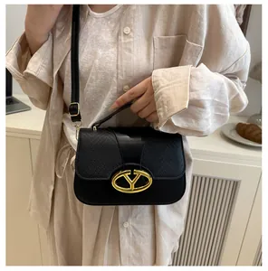 Detail of elegant black leather handbag with a gold metal lock and chic litchi texture