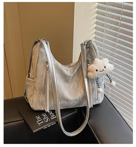 Gros plan d'un sac à bandoulière argenté brillant avec texture froissée et breloque