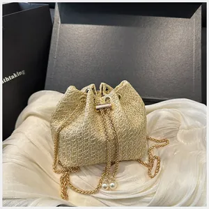 Détail du sac seau en paille avec chaîne dorée et breloques en perles blanches
