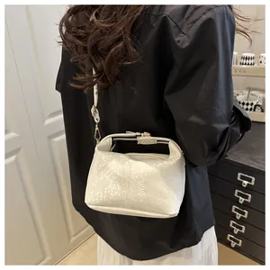 Detail of cream snake pattern mini crossbody bag with gold buckle on a shoulder