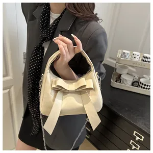 Détail du sac beige avec nœud et bandoulière chaîne argentée dans un décor de style
