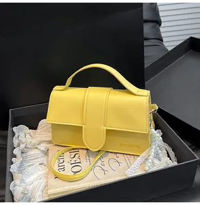 Detail of a bright yellow leather shoulder bag with a pearl chain and fashion logo engraving