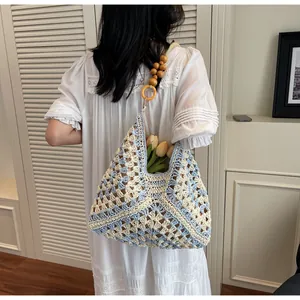 Detailed close-up of hand-woven crochet tote bag with wooden bead strap and blue patterns
