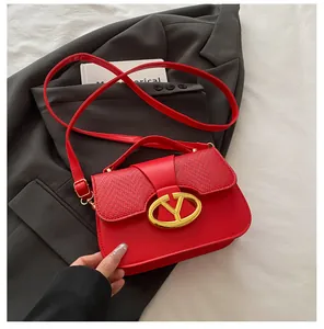 Detail of red leather crossbody bag with woven flap and gold oval buckle on a blazer
