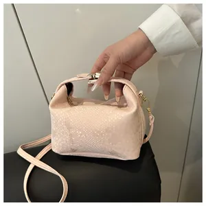 Detail of light pink snakeskin embossed texture and gold hardware on a crossbody bag