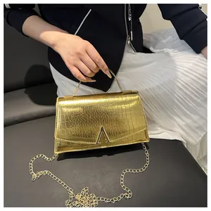 Detail showing gold crocodile embossed handbag with unique triangular metal clasp buckle