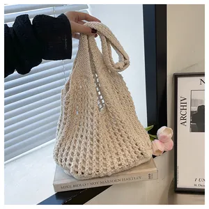 Macro detail of beige crochet hollow tote bag featuring intricate knit mesh texture