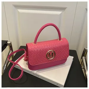 Détails de la texture tissée du sac à main rose fuchsia avec logo doré et poignée