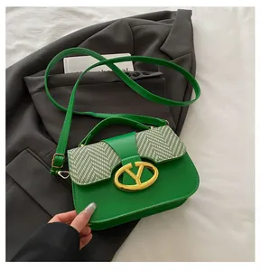 Detail of green leather handbag with houndstooth woven flap and gold V-shaped metal buckle