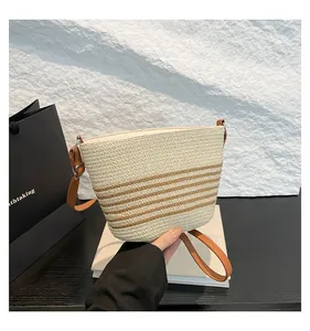 Close-up of straw bucket bag with brown stripes and adjustable leather shoulder strap