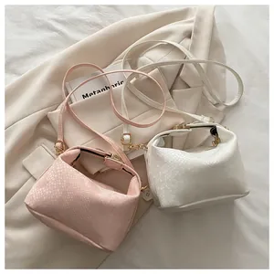 Close-up of mini snakeskin embossed bags in pink and white with golden metal hardware
