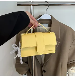 Macro view of yellow PU leather shoulder bag with fashion text and lace bow pendant