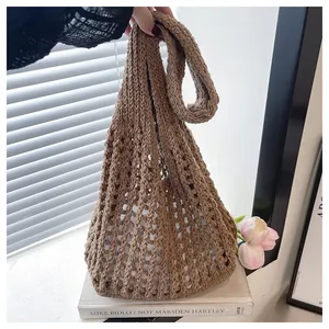 Detail of brown knitted tote bag featuring hollow mesh texture and wide shoulder strap