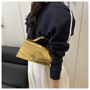 Detail of gold faux crocodile leather handbag featuring a metallic V-shaped buckle clasp