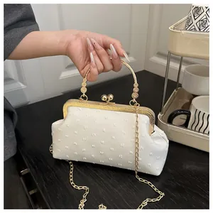 Dettaglio della borsa da sera vintage bianca con chiusura floreale dorata e tessuto a pois